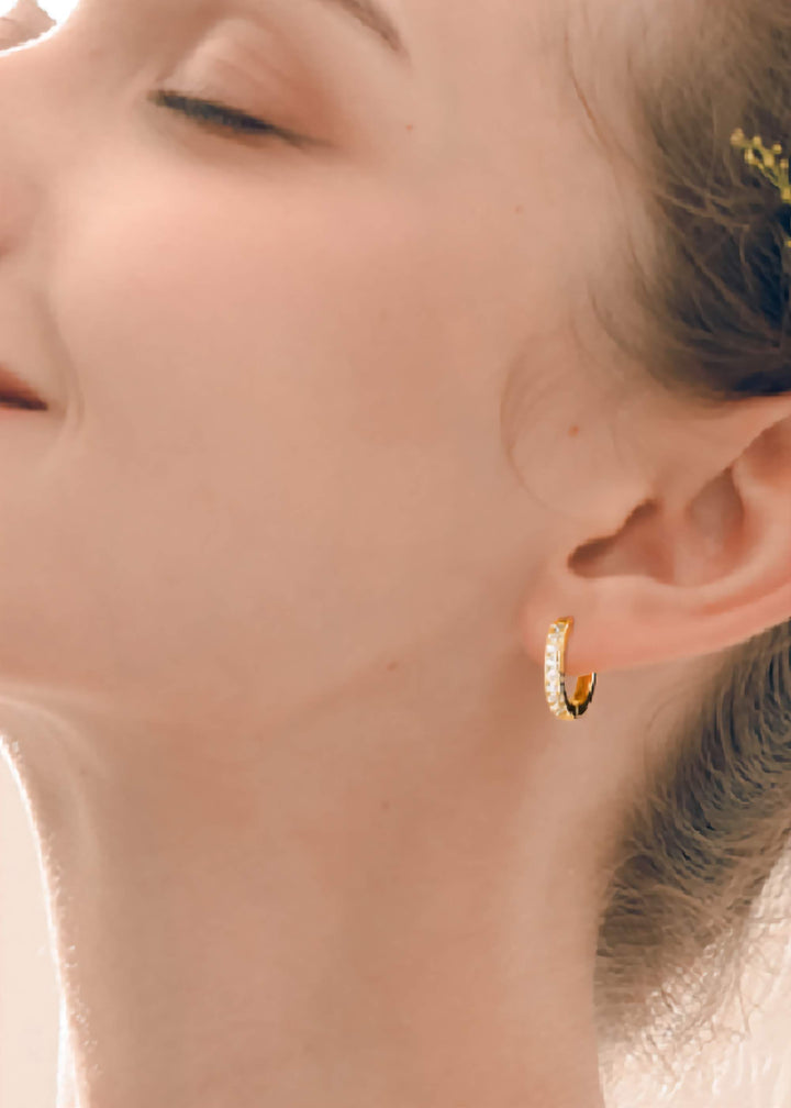 Close-up of a model wearing 14k Gold Plated Huggie Hoops earrings.