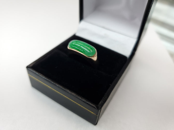 Green ring with gold band in a black jewelry box on a white background