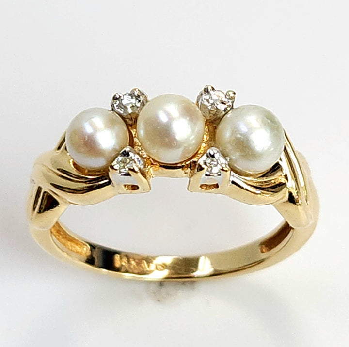 Gold ring with pearls and diamonds on a white background