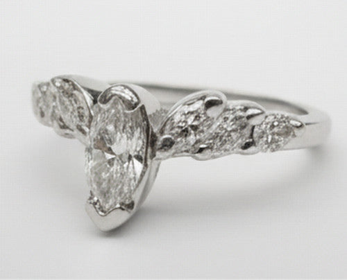 A silver-tone diamond ring featuring a marquise-cut center stone with smaller round diamonds along the shoulders and a split shank, shown on a light gray background.